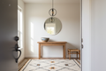 a residential entryway from the front door — console table, handmade ceramic bowl, mirror, chair, rug, centered light fixture