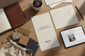 flat lay of a w+n year of hospitality welcome kit — studio letterhead, debossed notebook, material samples, quarterly calendar, client portal on tablet